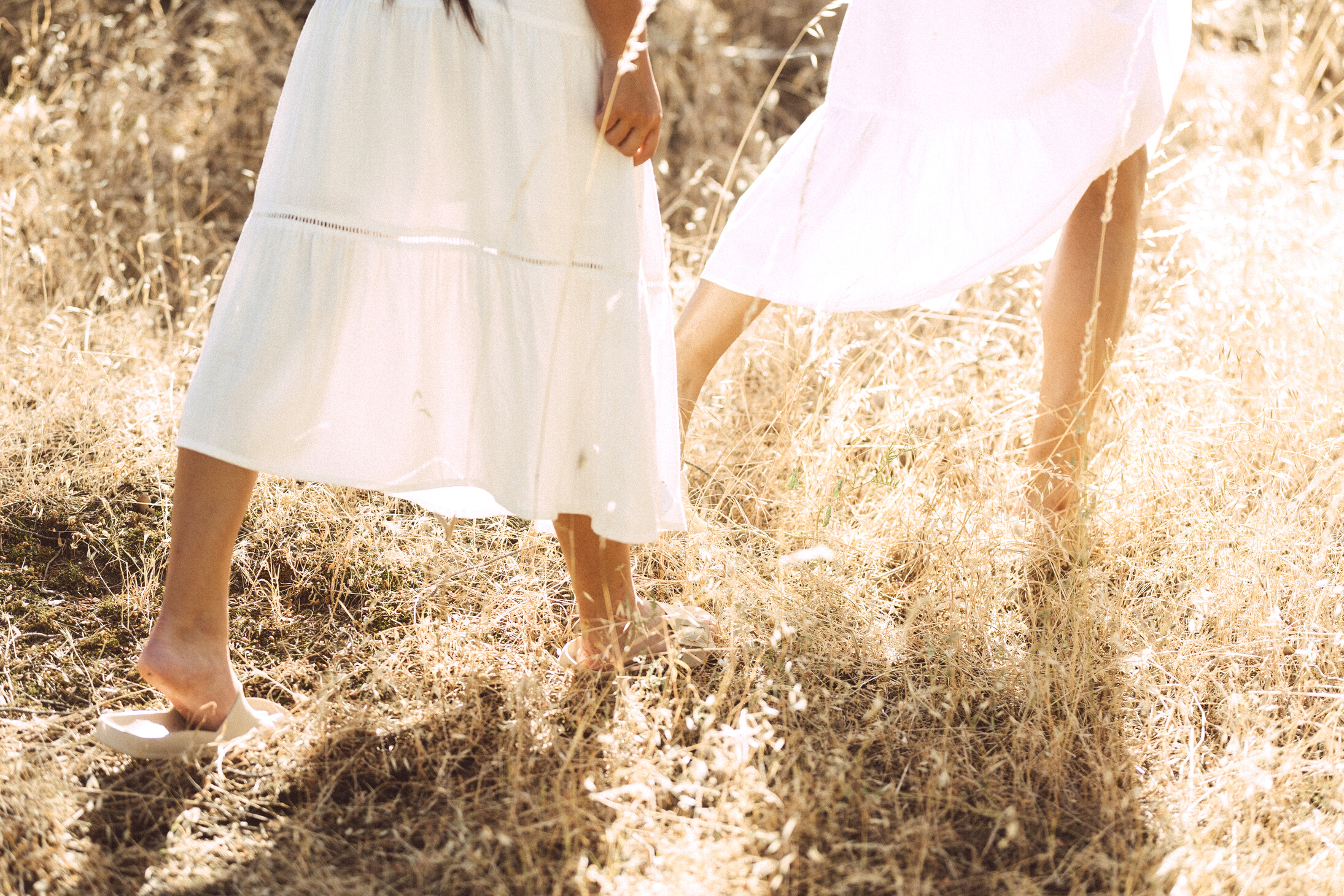 Two Women in Dresses Walking in the Field